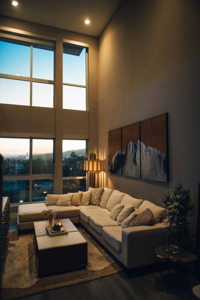 A living room at dusk with table lamps, wall sconces, and a ceiling fixture casting soft, warm light.