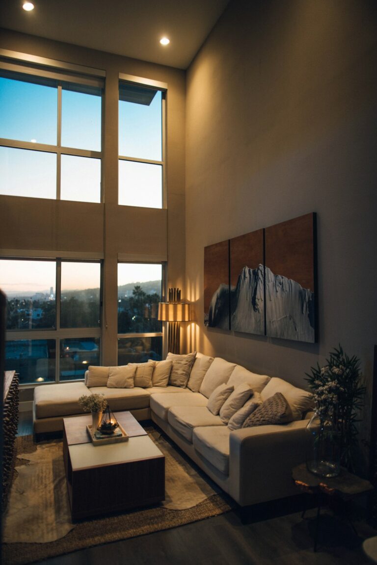 A living room at dusk with table lamps, wall sconces, and a ceiling fixture casting soft, warm light.