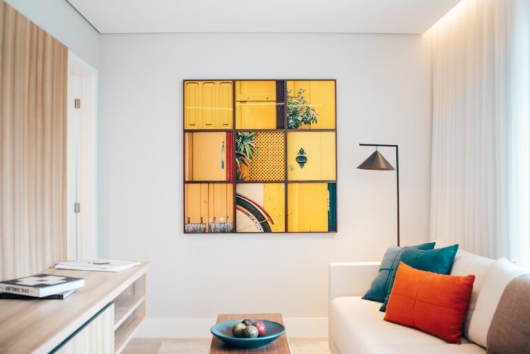 A bright living room wall featuring framed artwork, a round mirror, a small wall-hanging, and a few potted plants.