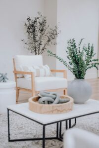 A bright living room with a styled coffee table holding books, a tray, ceramic decor, and a small plant.