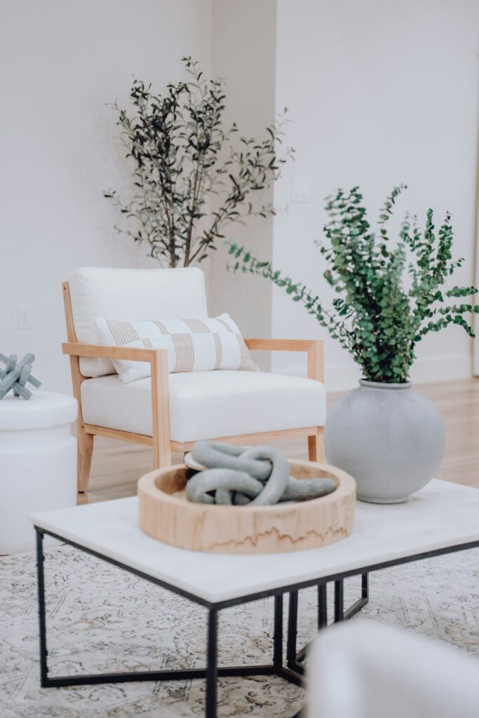 A bright living room with a styled coffee table holding books, a tray, ceramic decor, and a small plant.